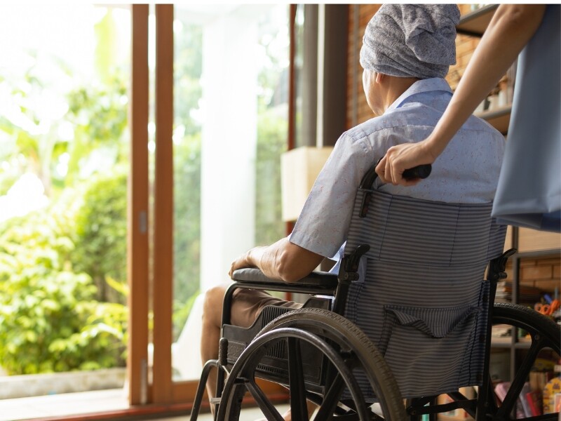 man in rolstoel kijkt uit raam