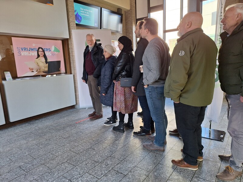 Een lange rij wachtende mensen aan een geïmproviseerd loket voor vrijwilligers in het station van Zele.