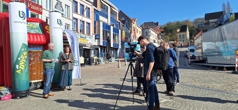 Op de Markt in Geraardsbergen staan Johan Vyverman en Griet Blaton voor een wervelwindcabine tijdens de persactie van de Week van de Vrijwilliger