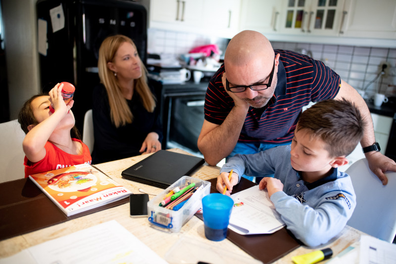 Vader helpt kind met huiswerk aan de keukentafel
