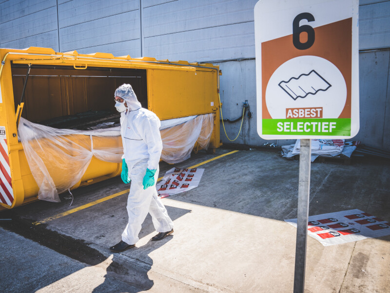 Werknemer aan asbestcontainer in containerpark