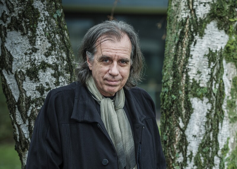 Dirk De Wachter, psychiater en psychotherapeut kijkt in de camera met bomen op achtergrond