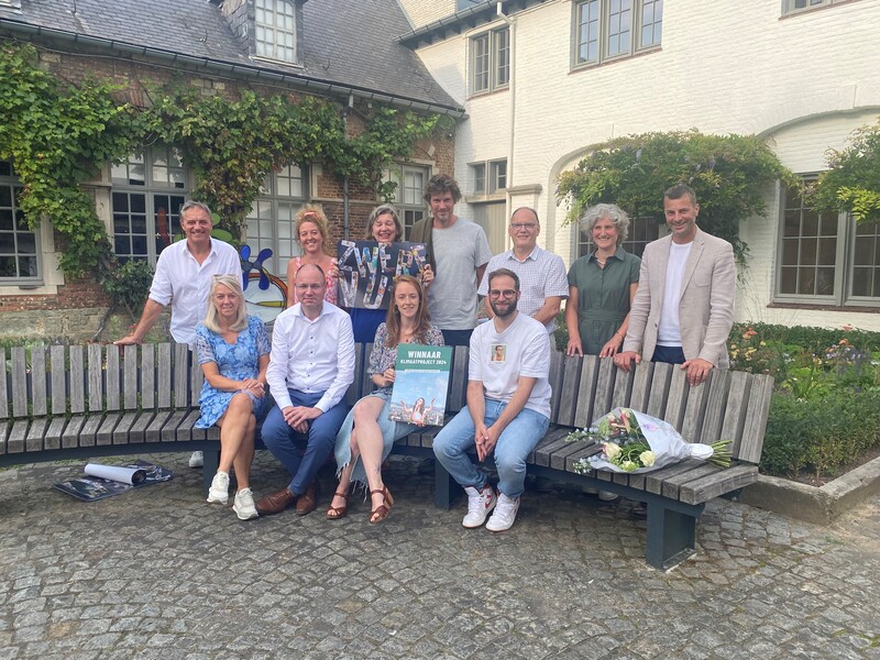 De winnaars van de Duurzame prijs van de stad Ronse poseren in groep aan een houten zitbank.