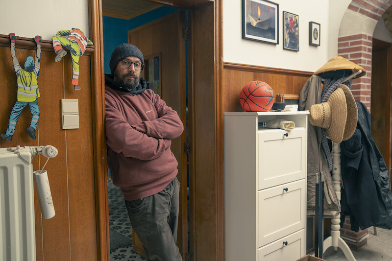 Grafittikunstenaar Jaune in deuropening naast sjablonen van zijn werk