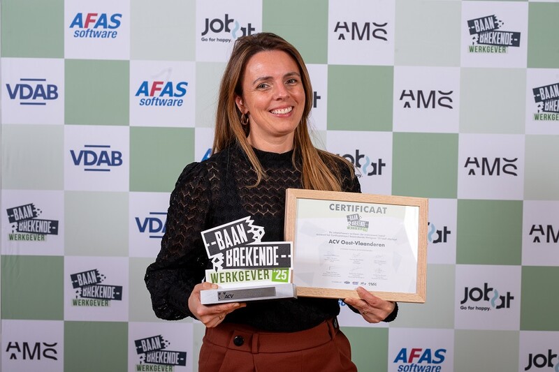 ACV-werkneemster Veerle Van Oudenhove poseert fier met het certificaat 'Baanbrekende Werkgever 2025' in de hand.