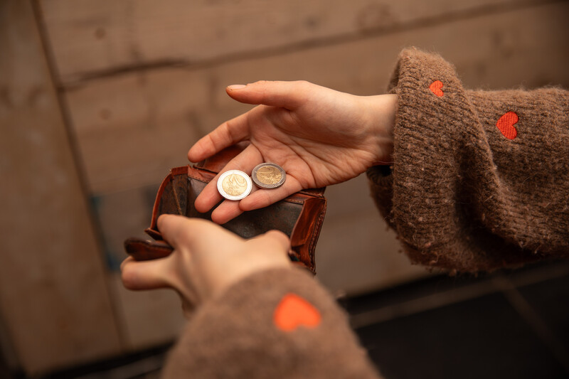 lege portemonnee met enkele twee-eurostukken in de hand