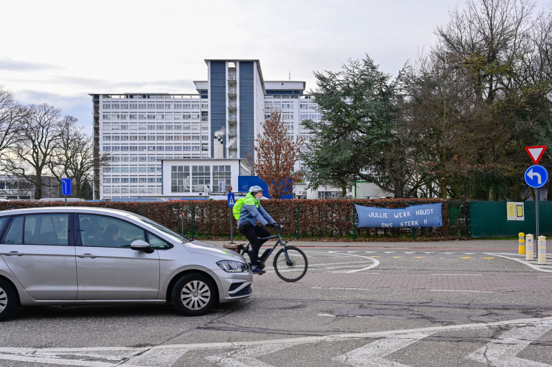 auto en fiets op straat met in achtergrond een ziekenhuis