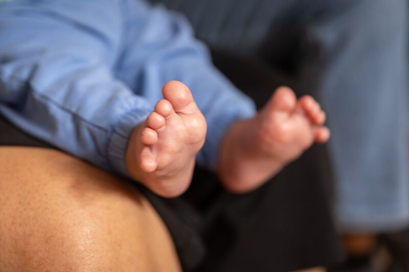 We zien de voetjes van een pasgeboren baby op schoot bij iemand.