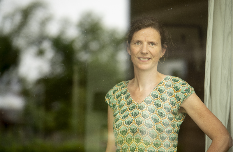 Vrouw, Anneleen de Bonte, kijkt vanachter raam naar buiten.
