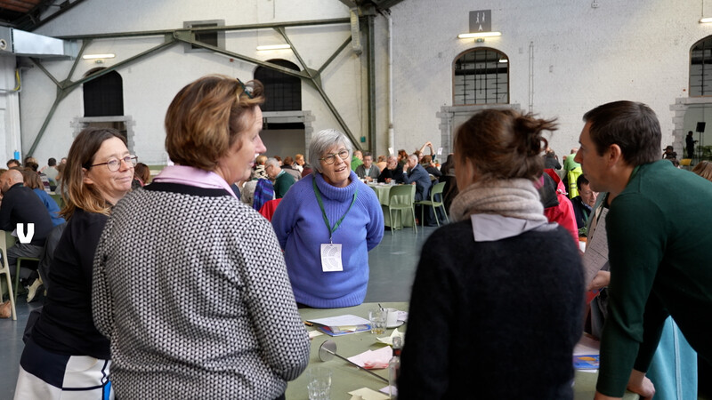 mensen staan recht aan tafel in grote zaal