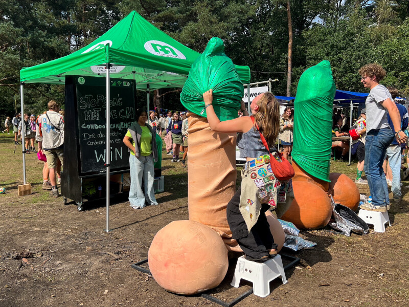 Jongeren trekken condooms over reusachtige penisbeelden tijdens studentevenement