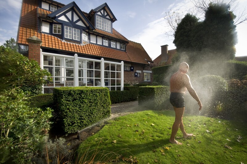 man in zwembroek neemt douche voor villa in Knokke