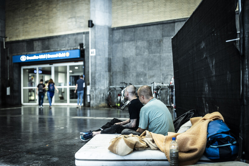 Twee dakloze mannen op de grond voor station Brussel Zuid