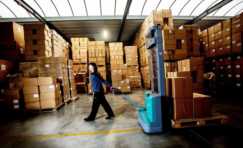 magazijn met arbeidster die transpallet bestuurt