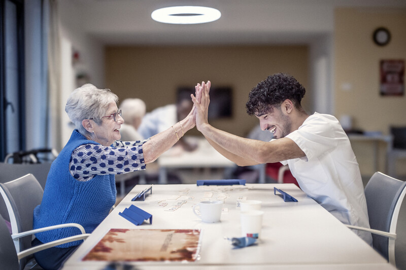 een bewoner en verzorger in woonzorgcentrum spelen samen Rumikub