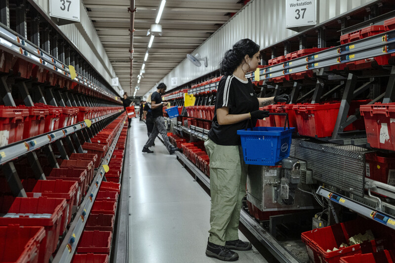 Een vrouw werkt in een magazijn en doet aan order picking