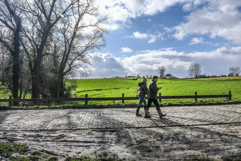 Twee wandelaars op een landelijke weg tussen de velden