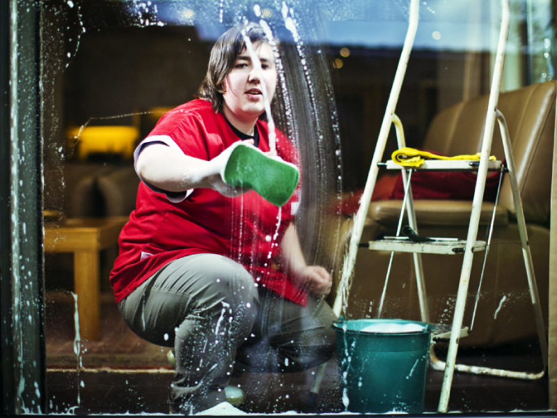 Huishoudhulp die het raam poetst