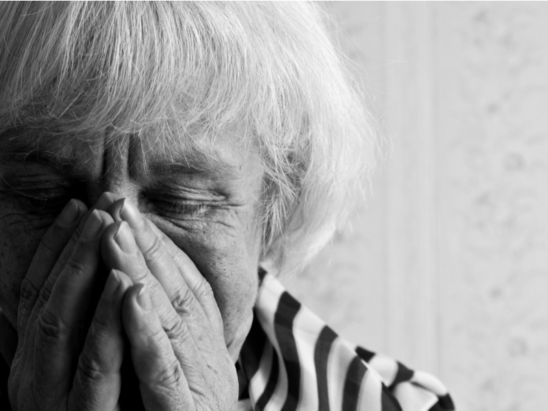 Een oudere vrouw is verdrietig en houdt haar handen voor haar gezicht