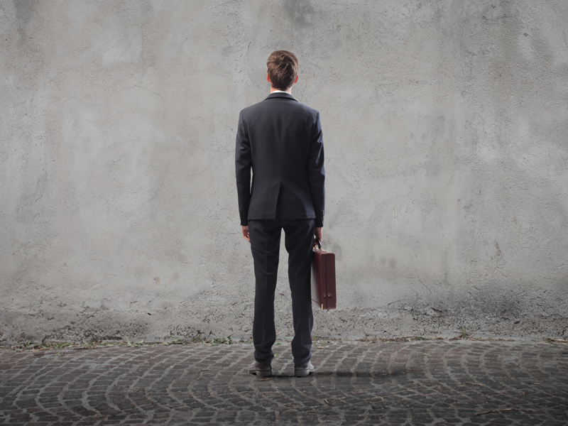 Man met aktetas voor betonnen muur
