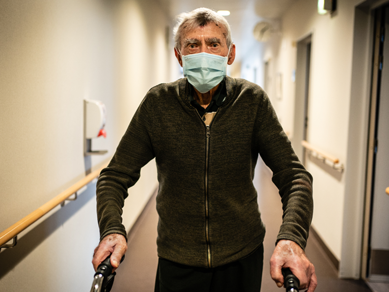 Bewoner woonzorgcentrum die met doordringende blik in gang staat