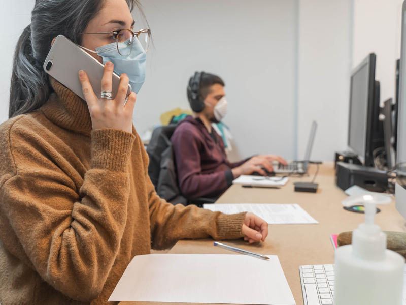 Vrouw en man werken met mondmasker in kantoor