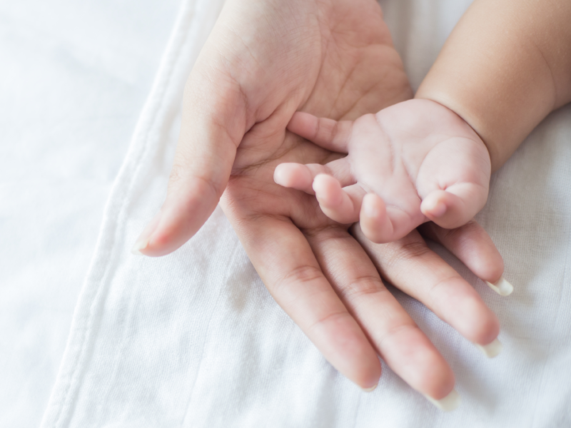 Hand van baby in hand van moeder