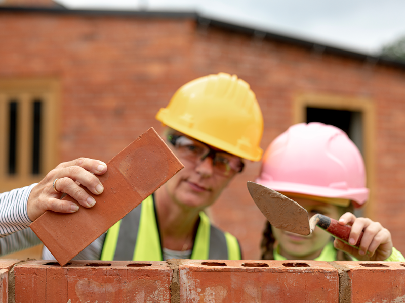 Een vrouw bouwt samen met haar dochter een muur