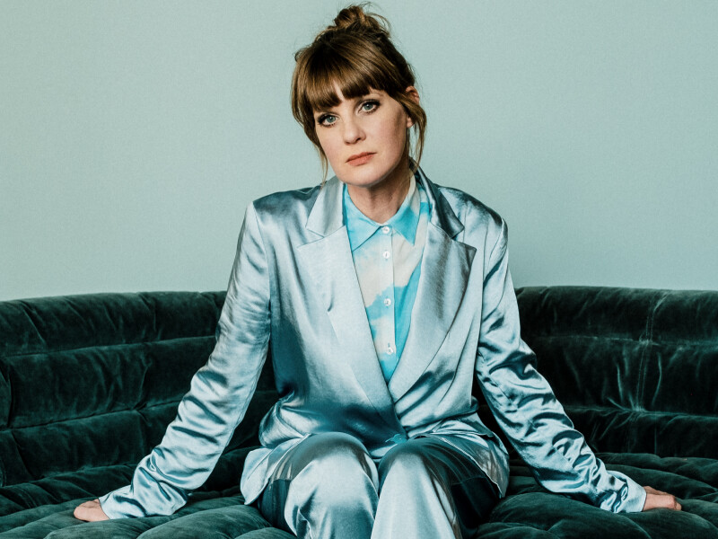 Drumster Isolde Lasoen in een zetel voor een blauwe muur