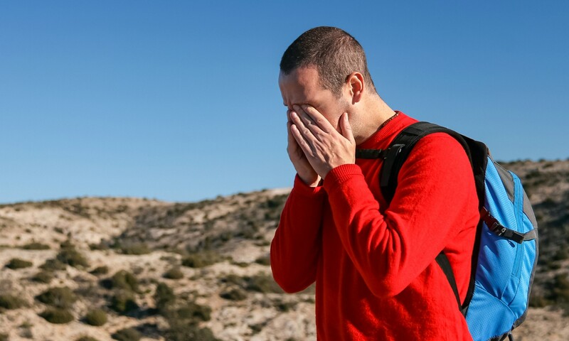 man met handen voor gezicht op het strand