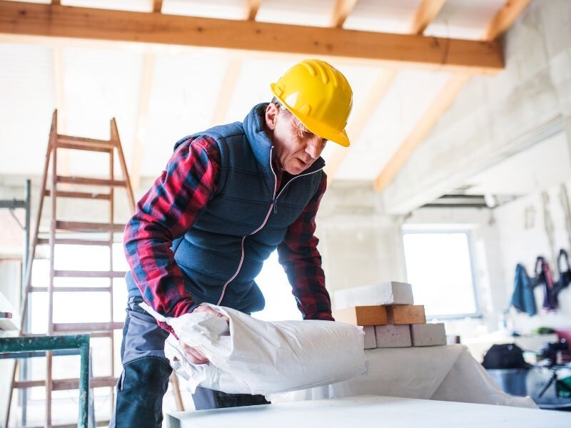 oudere man met helm werkt op bouwwerf