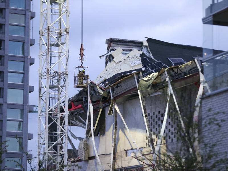 Twee bouvakkers in bak aan hijskraan inspecteren dak van ingestorte school Nieuw Zuid Antwerpen