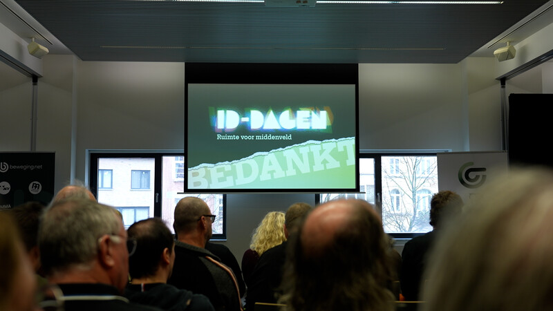 zaal met mensen die lezing bijwonen en scherm met visual van ID-dagen