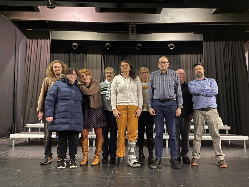 Negen acteurs staan op een podium klaar om hun toneelstuk te brengen.